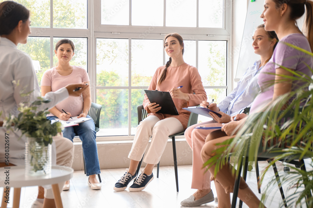 Young pregnant women with clipboards at course for expectant mothers