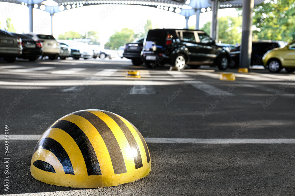 Limiter with yellow and black stripes on parking lot, closeup