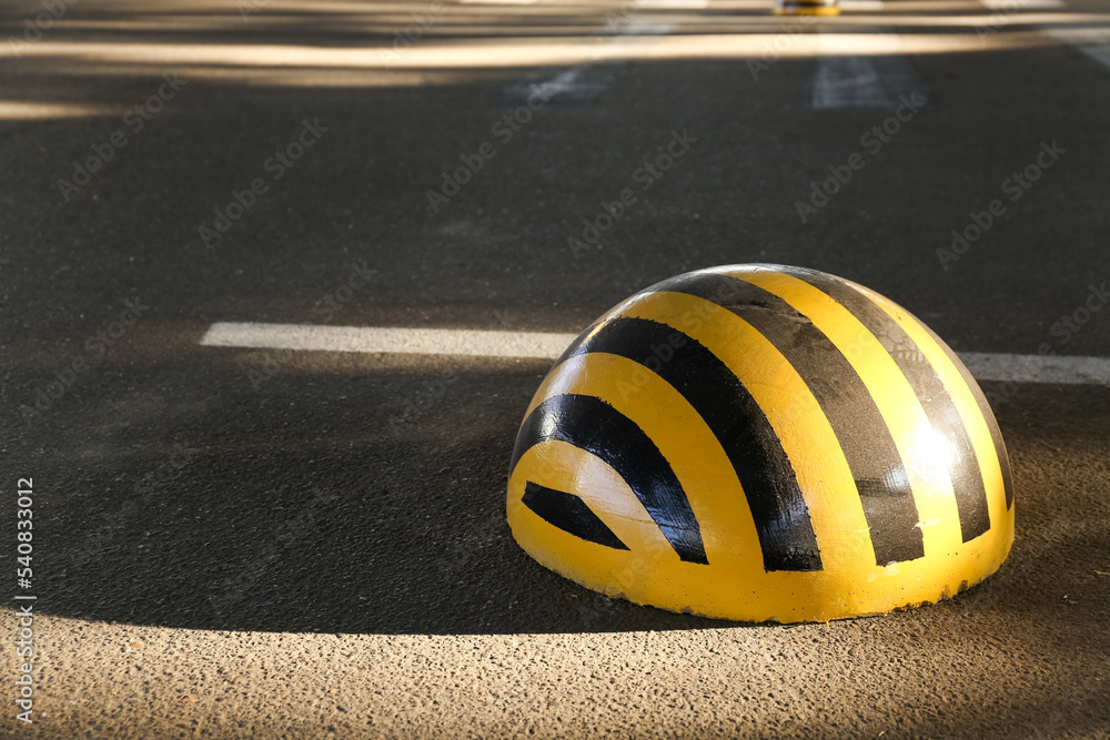 Limiter with yellow and black stripes on parking lot, closeup