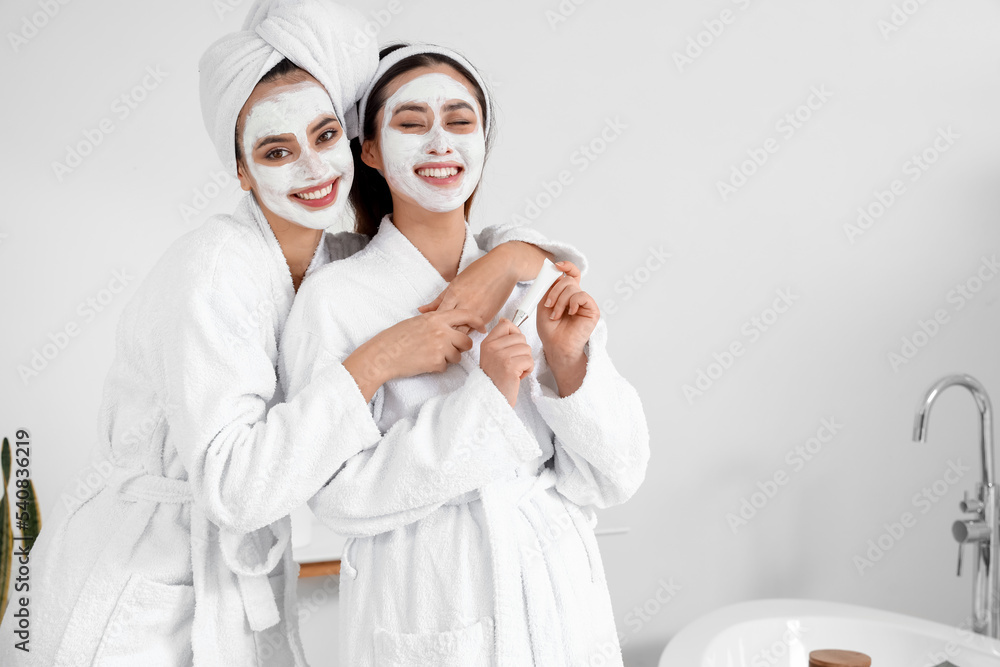 Beautiful young women with applied facial masks in bathroom