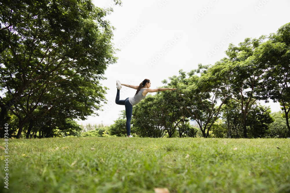 亚洲女性在公园里做瑜伽姿势。健康生活方式和户外生活的概念。