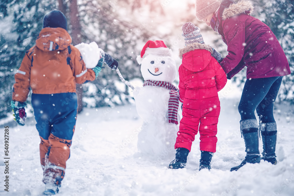 一家人在雪地公园里骗了一个可爱的雪人。