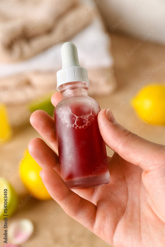 Female hand with bottle of vitamin C serum, closeup