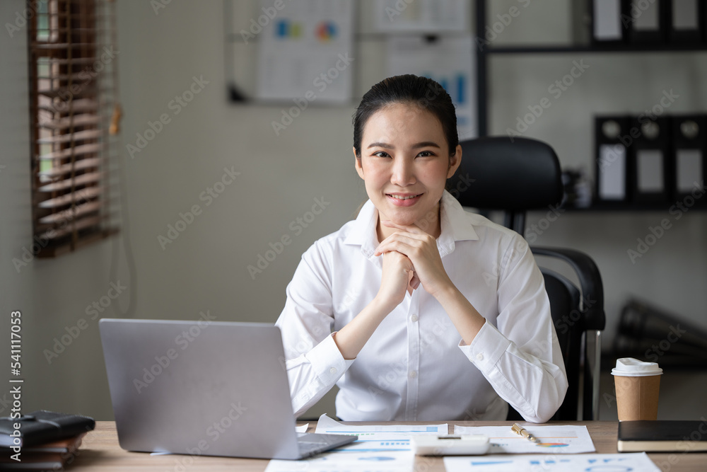 可爱的亚洲女人在办公室用笔记本电脑喝茶