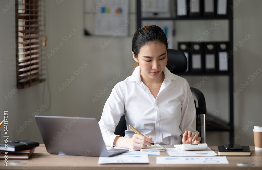 可爱的亚洲女人在办公室用笔记本电脑喝茶