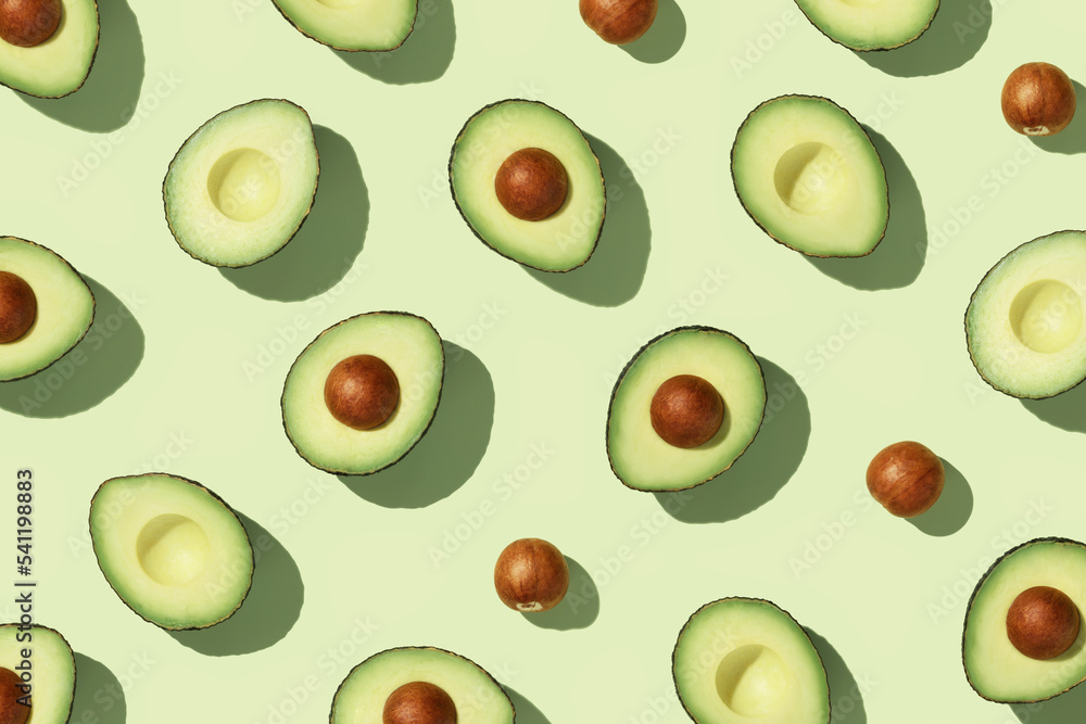 Avocado on green background pattern top view flat lay