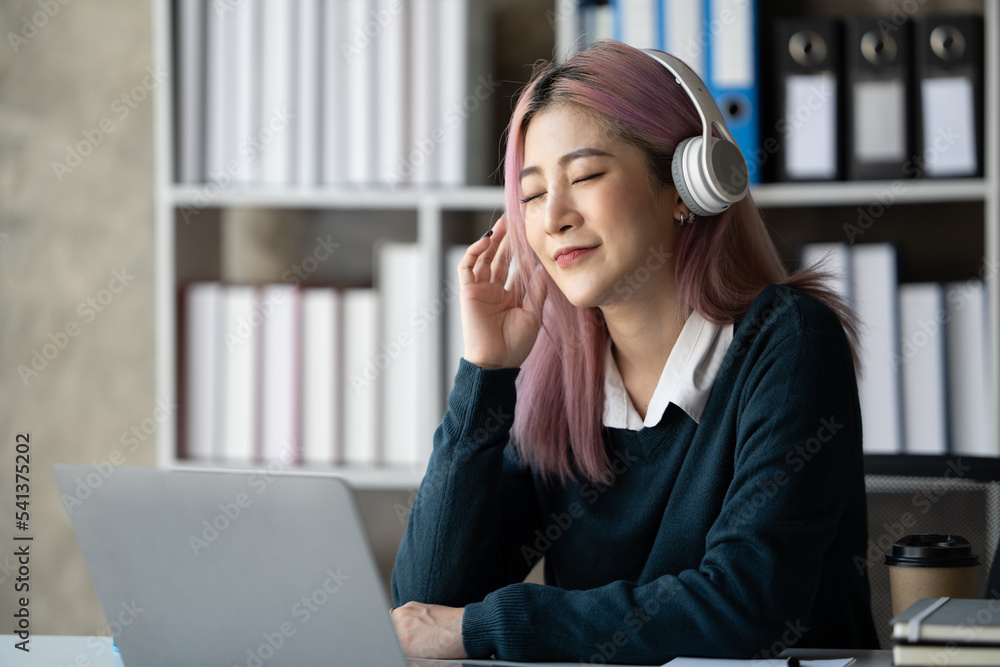 一位年轻的女学生坐在桌子旁，学习时使用耳机。