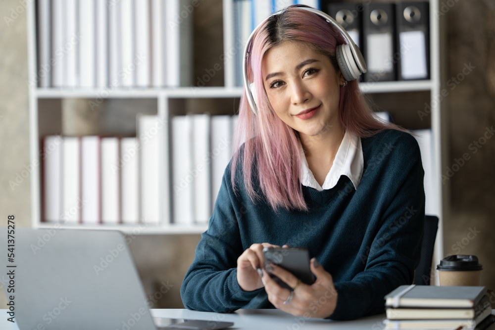 一位年轻的女学生坐在桌子旁，学习时使用耳机。