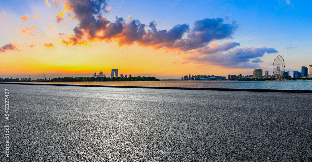 日落时分，中国苏州的沥青道路和城市天际线，以及现代化的建筑。