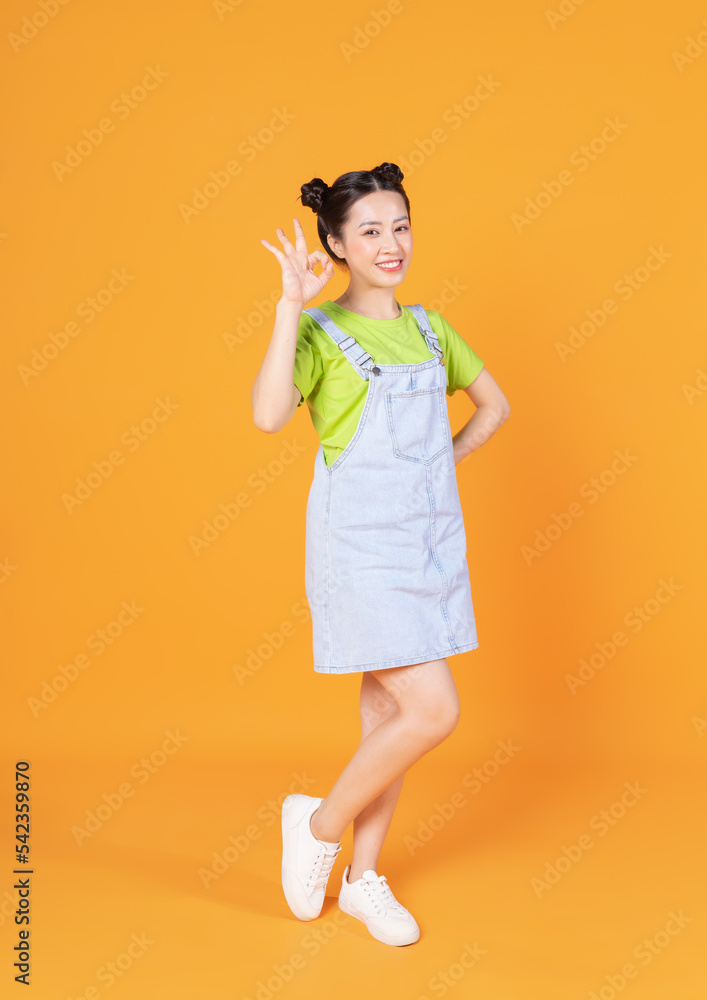 Full length image of young Asian woman standing on background