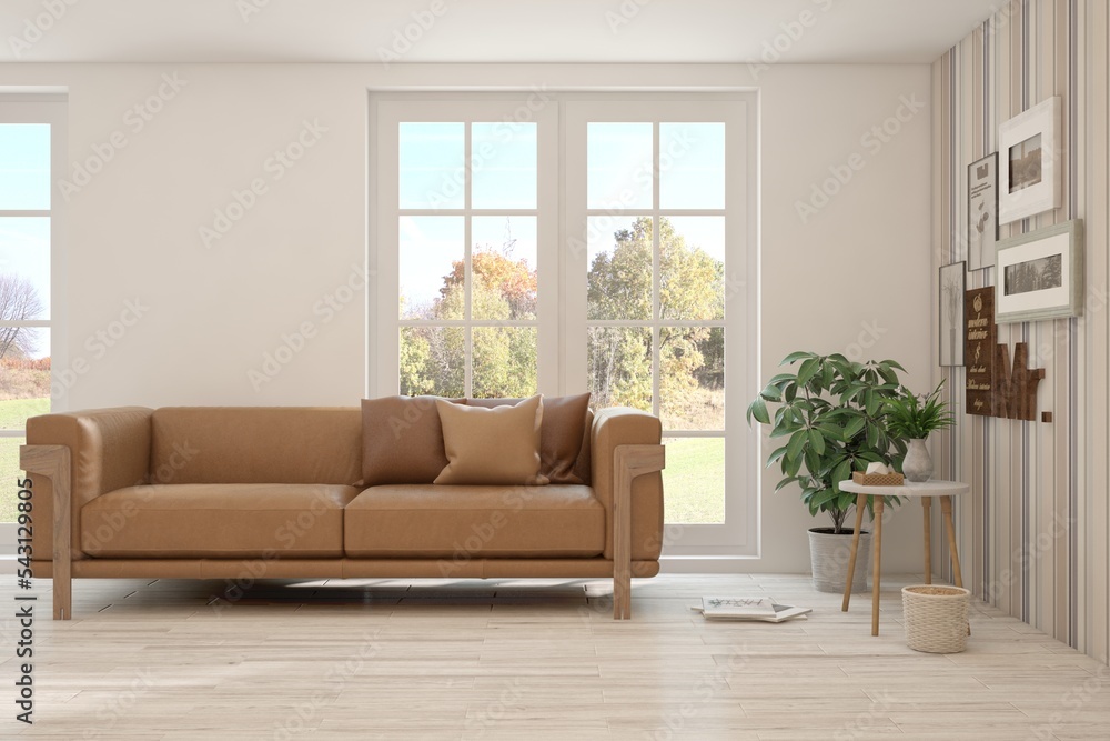 Stylish room in white color with sofa and autumn landscape in window. Scandinavian interior design. 