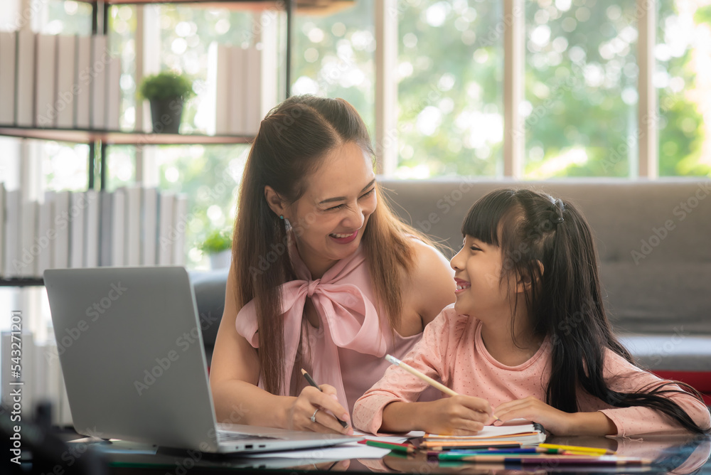 年轻的亚洲母亲很高兴看到小学级别的可爱女孩在生活中上网课