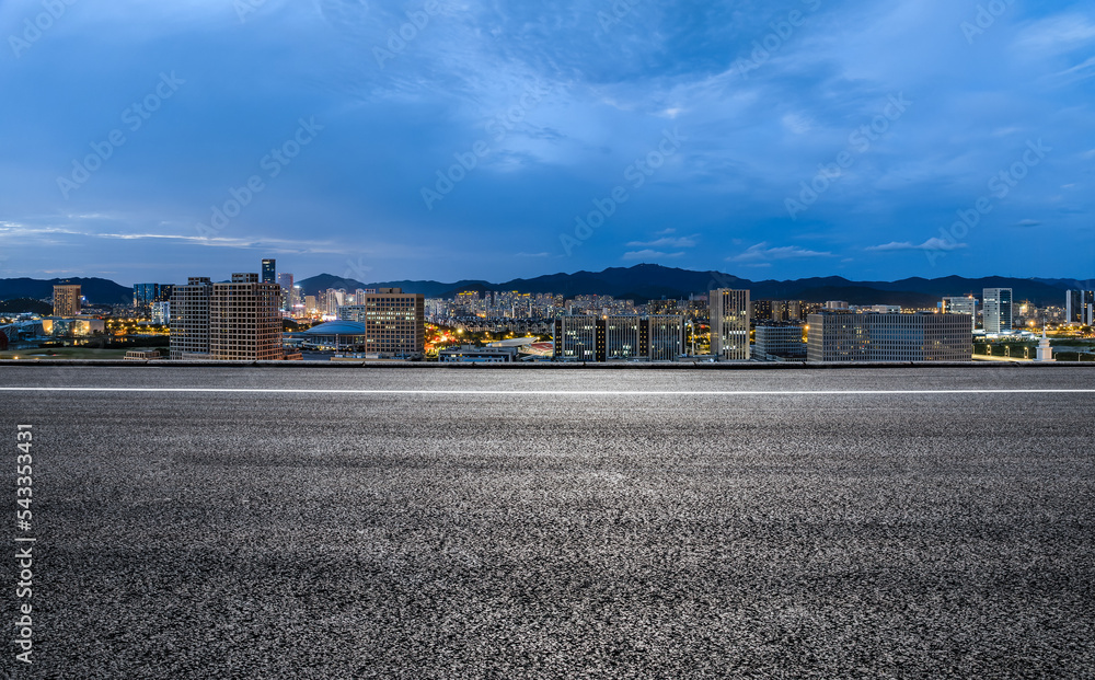 中国浙江舟山夜晚的沥青道路和城市天际线与建筑。