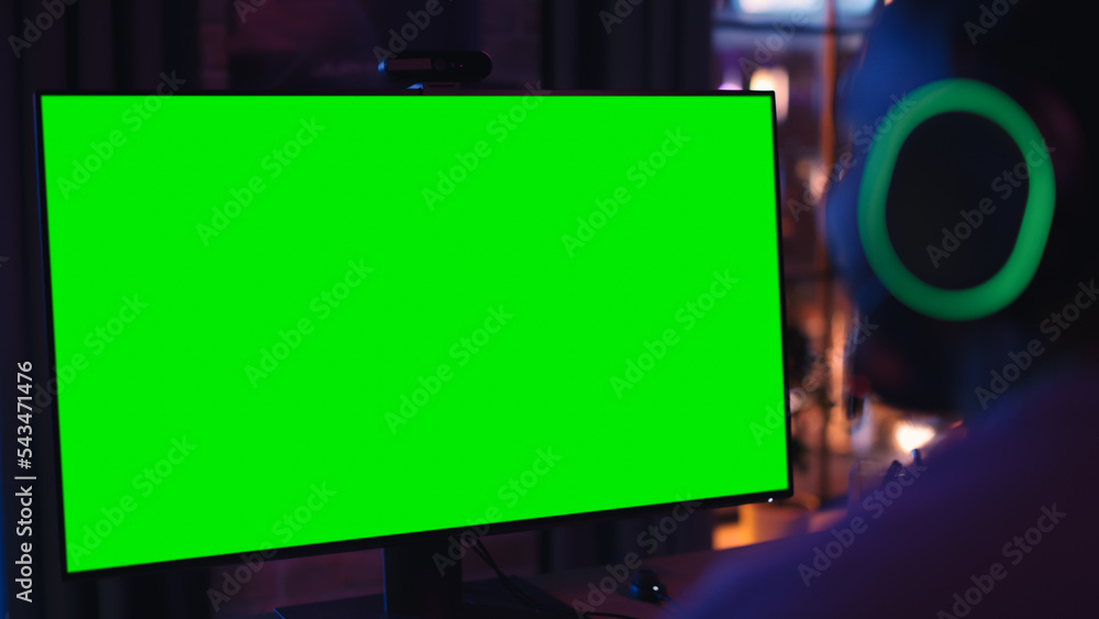 Excited Black Gamer Playing Online Video Game with a Mock Up Green Screen on His Powerful Personal C