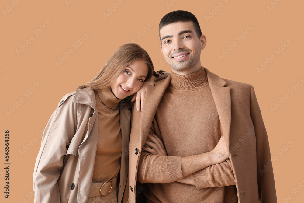 Fashionable young couple in autumn clothes on beige background