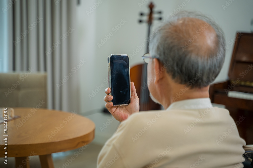 坐在轮椅上的老人用智能手机与他的孩子和孙子在线交谈