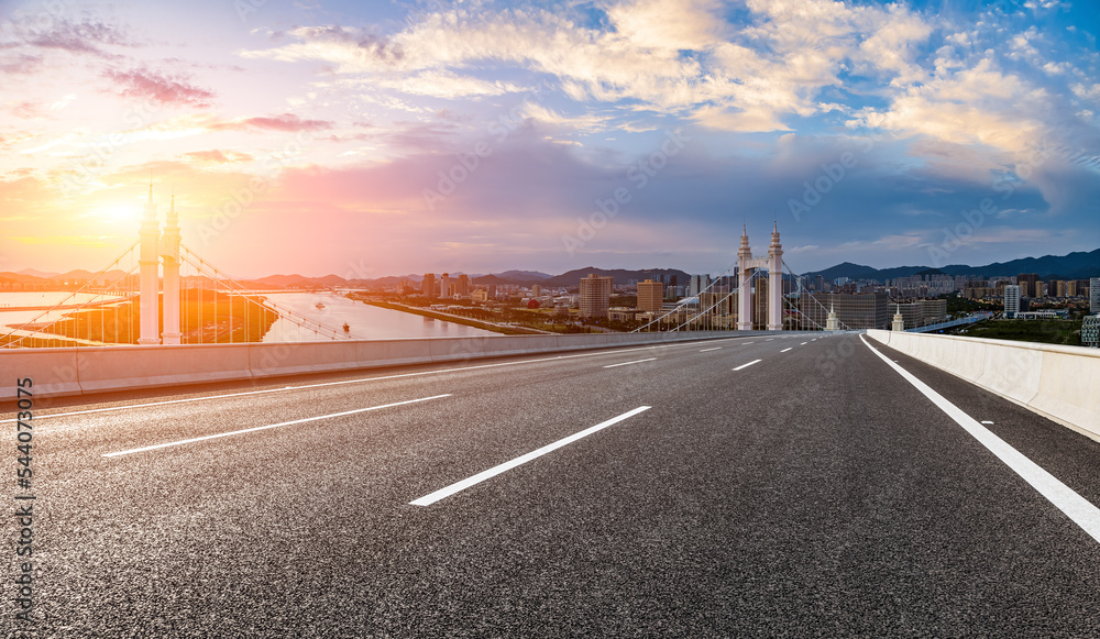 Asphalt road and bridge with city skyline at sunset in Zhoushan, Zhejiang, China.