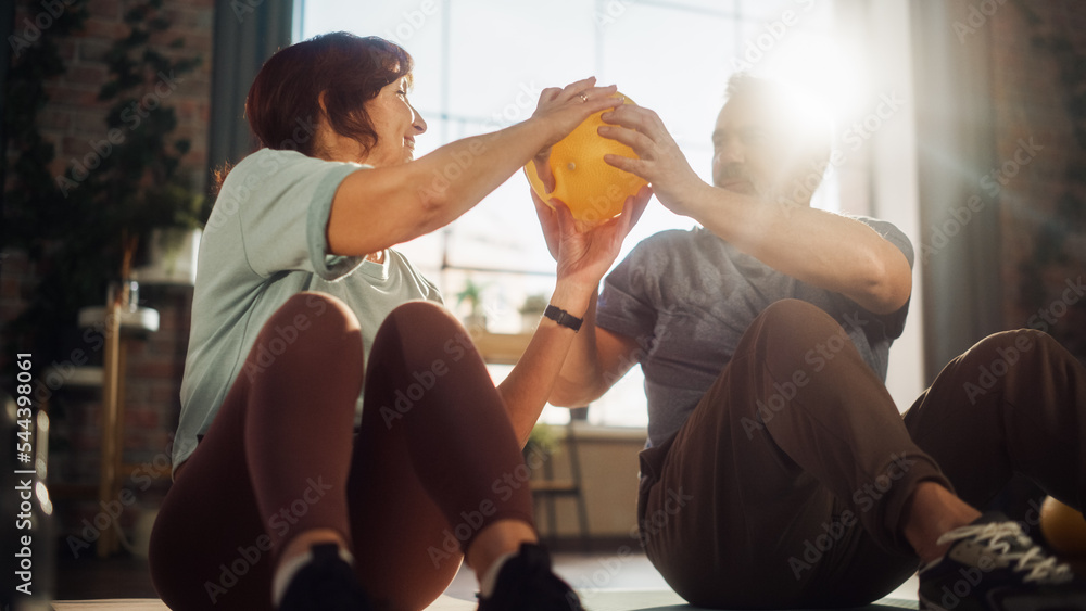 Happy Senior Couple Doing Core Strengthening Exercises Together at Home in Sunny Living Room. Senior