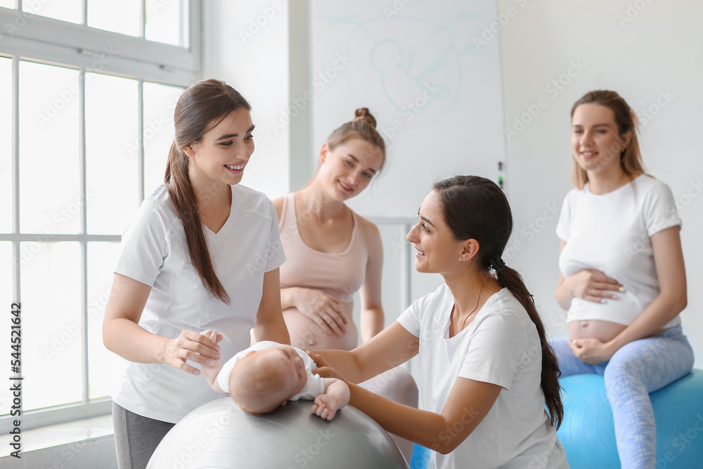 带着婴儿和孕妇的女教练在健身房训练