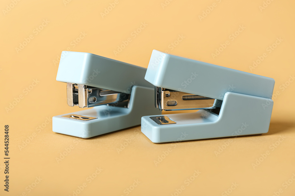 Office staplers on color background