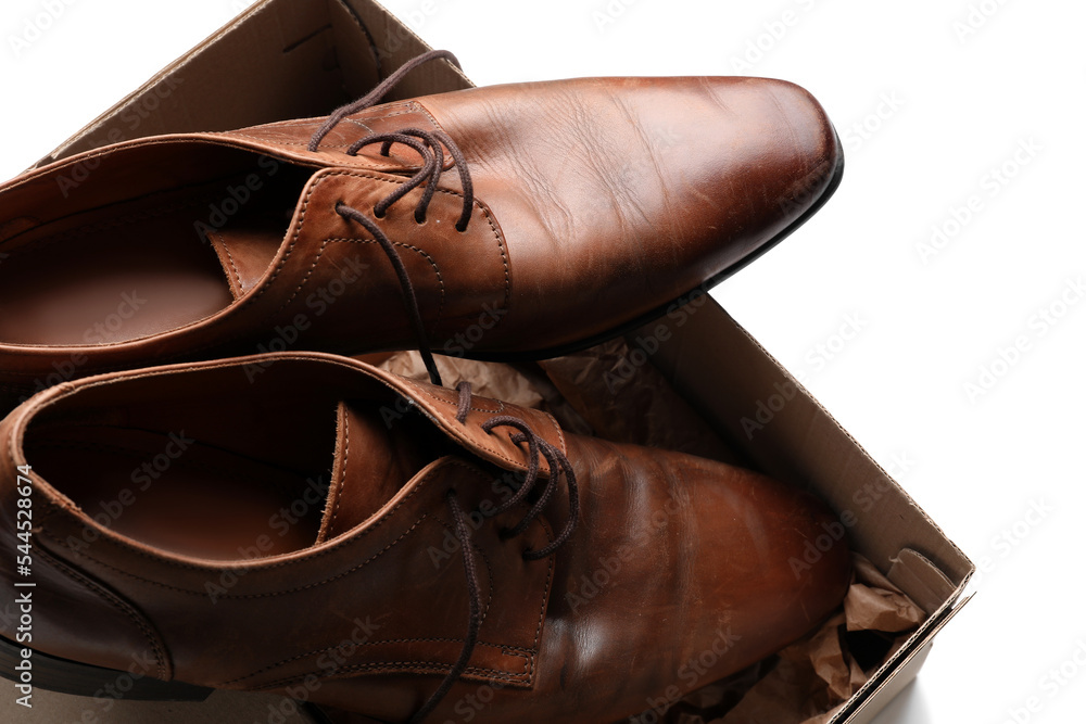 Cardboard box with brown shoes on white background, closeup