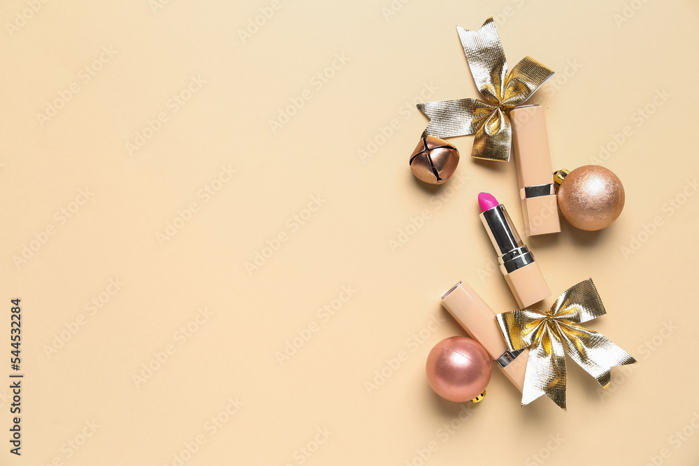 Lipsticks with Christmas balls, bell and bows on beige background