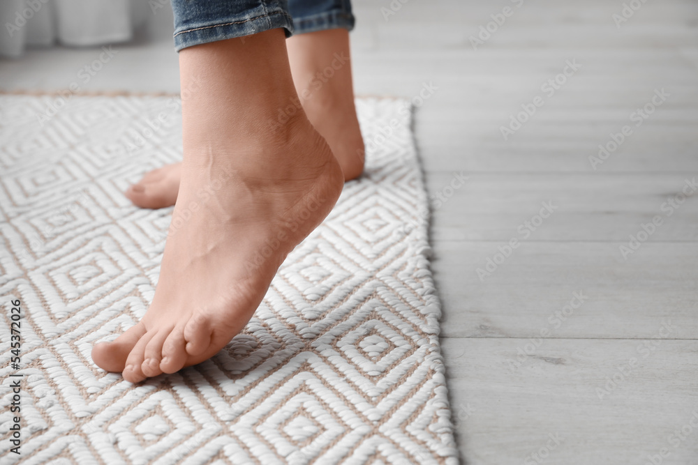 Female bare feet on rug, closeup