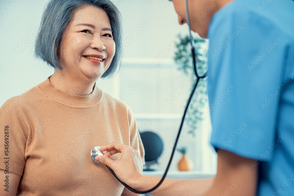 A contented retired senior woman being exterminated by her caregiver with a stethoscope at home. Med