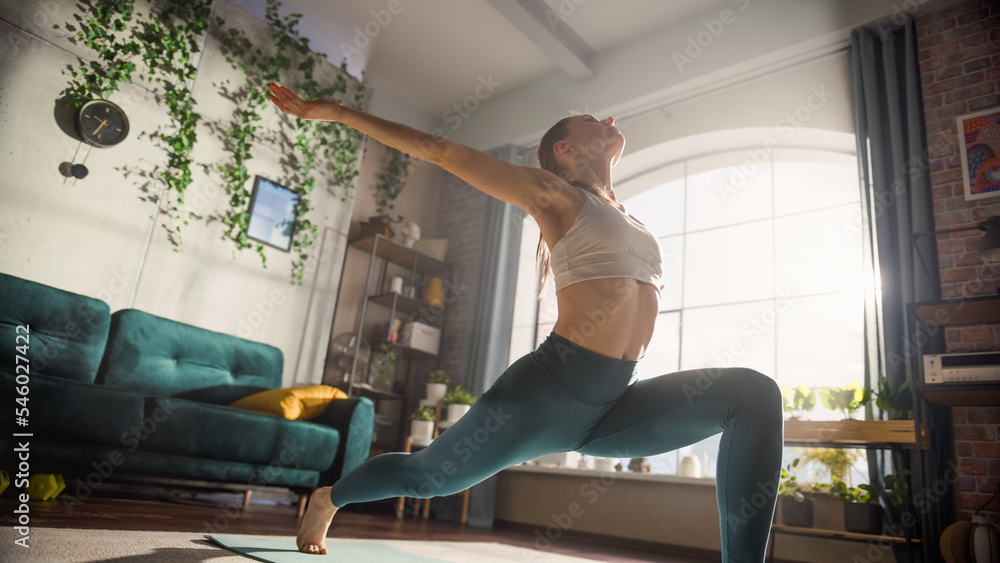 Young Beautiful Female Exercising, Stretching and Practising Yoga Early in the Morning in Her Bright