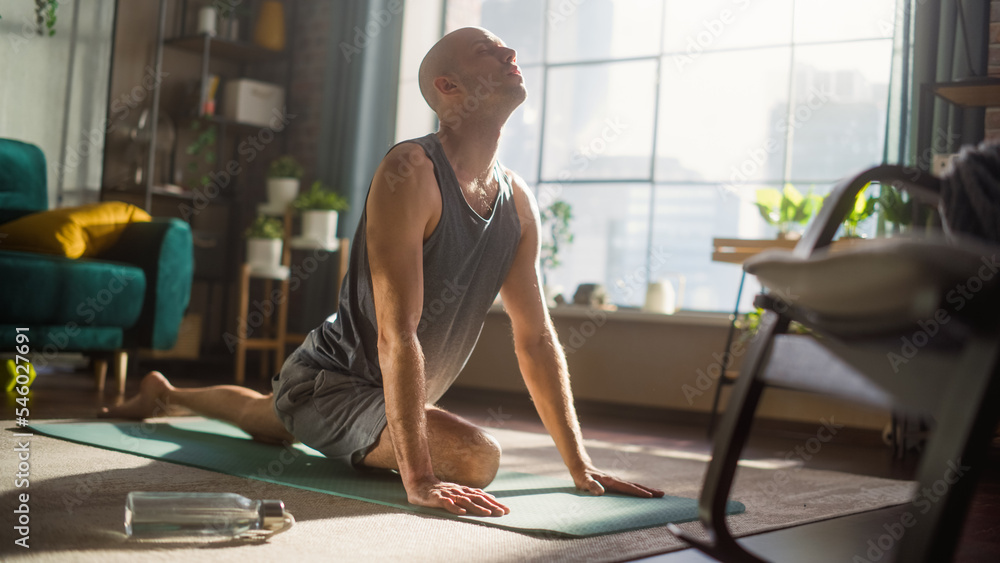 Young Athletic Man Exercising, Stretching and Practising Advanced Yoga in the Morning in His Bright 