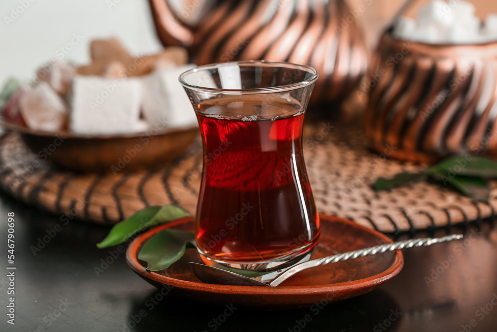 Saucer with glass of Turkish tea and spoon on table in room, closeup