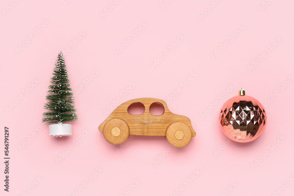 Toy car with Christmas tree and ball on pink background