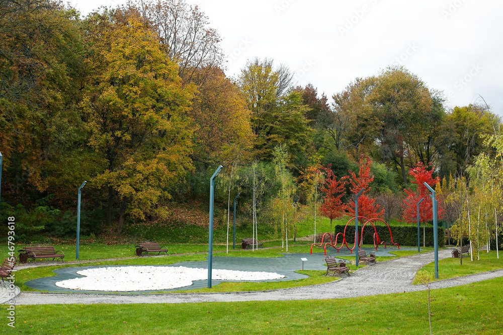 View of autumn park with benches, street lamps and climbing net