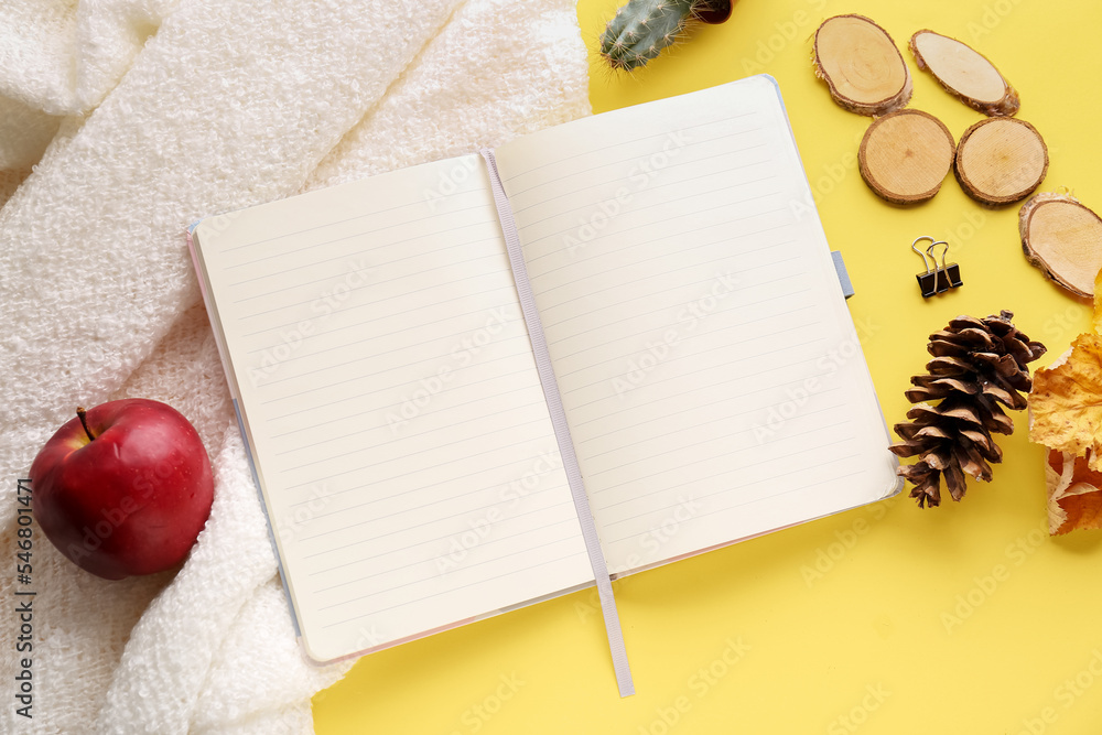 Blank open notebook, apple, pine cone and plaid on color background