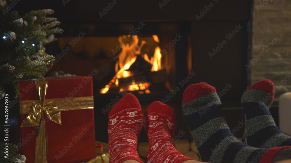 CLOSE UP: Couple rest by fireplace and warming up their feet in Christmas socks