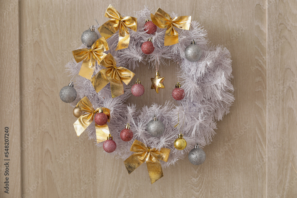 Wooden door with Christmas wreath in room, closeup