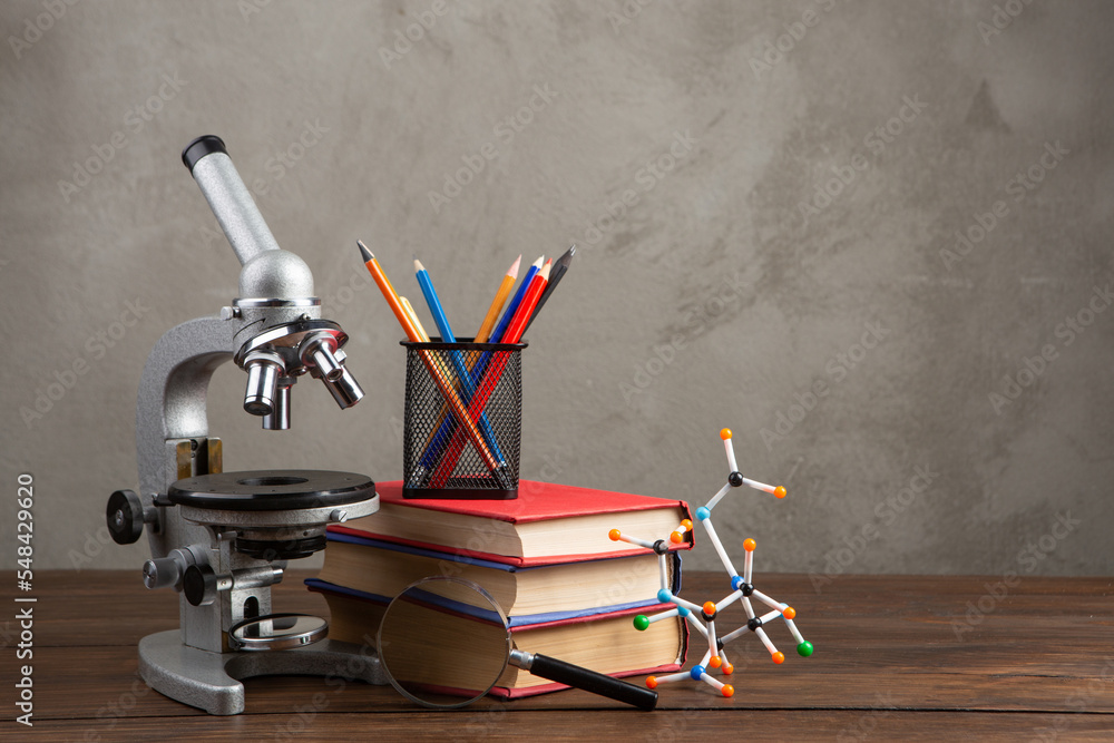 Back to school - books and microscope on the wooden desk in the auditorium, Education concept