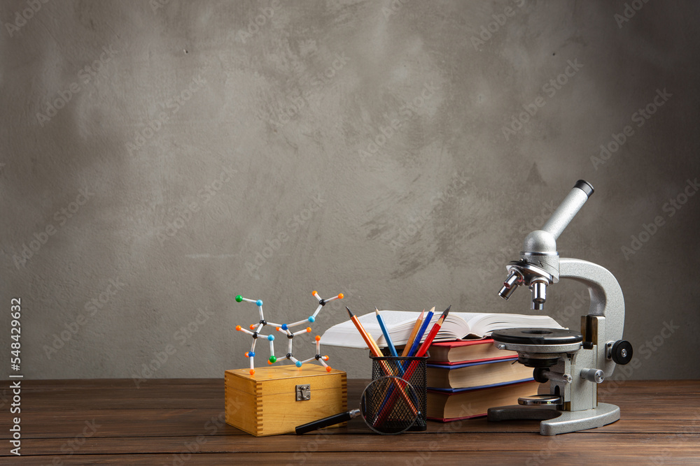 Back to school - books and microscope on the wooden desk in the auditorium, Education concept