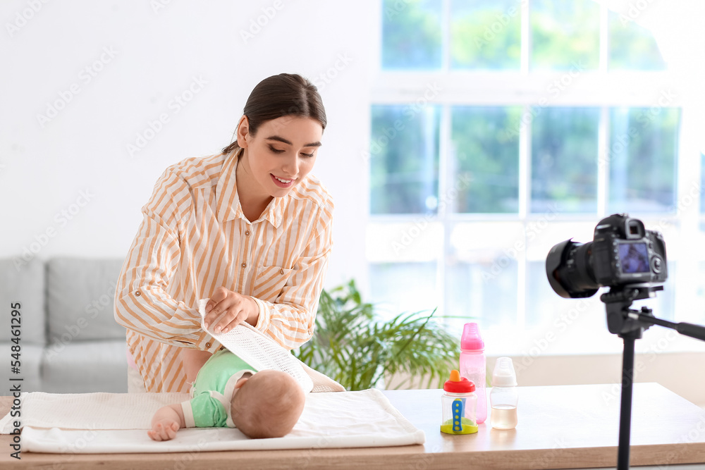 年轻女子在家录制视频课程时襁褓中的婴儿