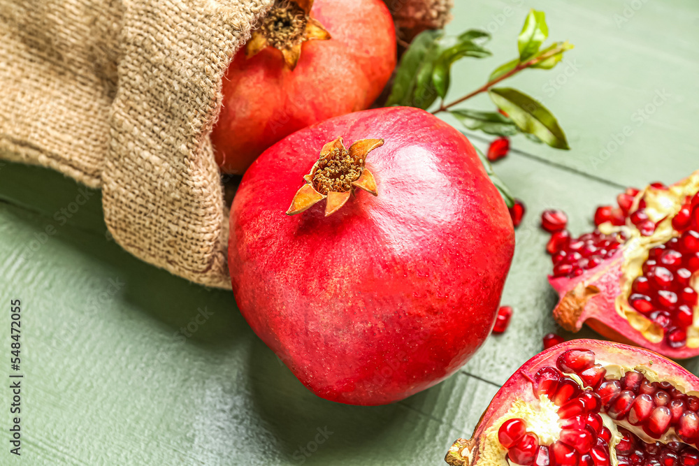 Sack bag with ripe pomegranates on color wooden background, closeup