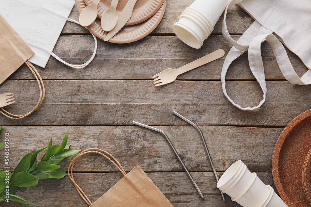 Eco tableware, different bags and plant branch on wooden background