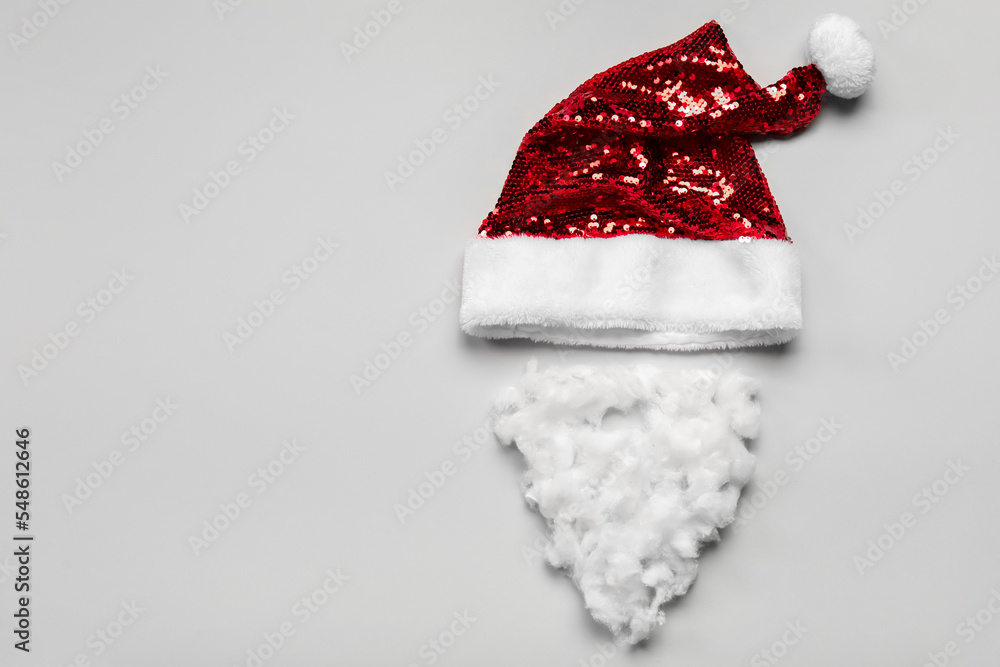 Santa hat and beard made of cotton wool on light background