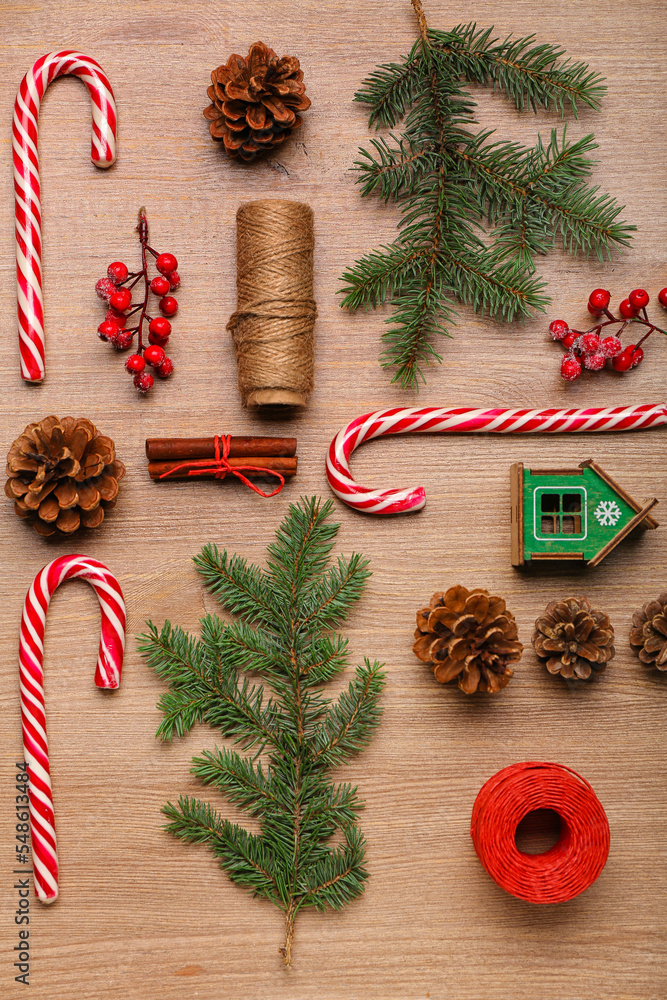 Composition with sweet candy canes, fir branches and cones on wooden background