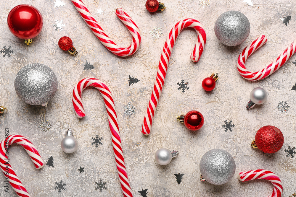 Composition with sweet candy canes and beautiful Christmas balls on light background