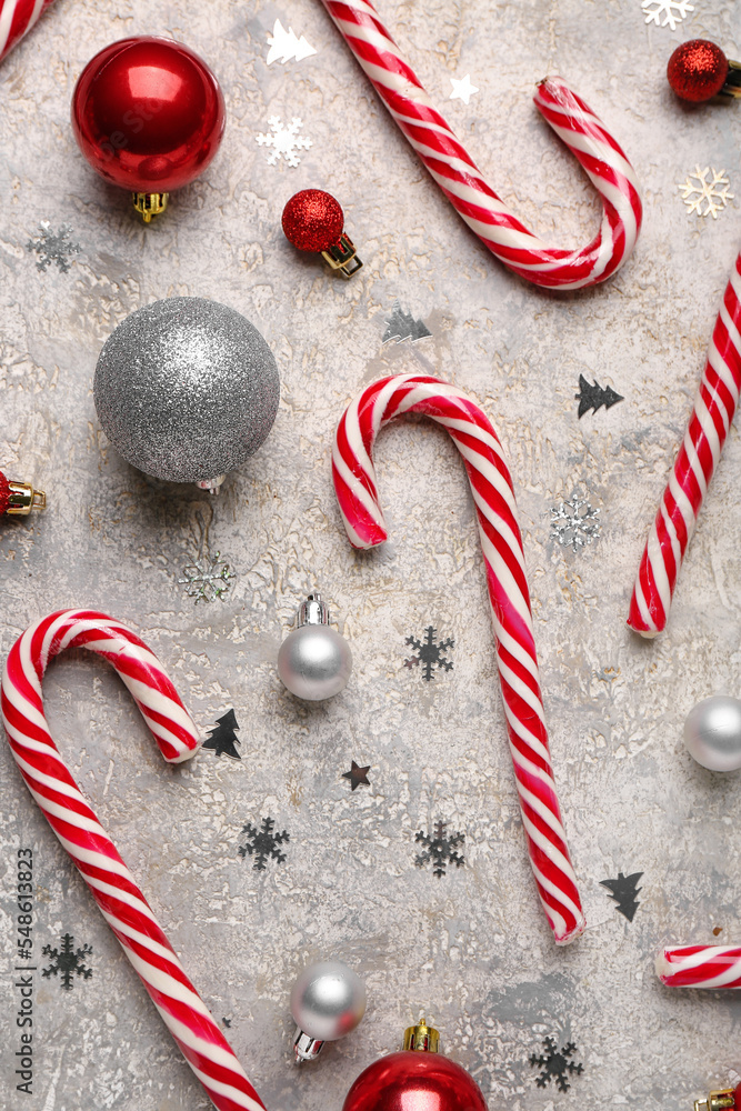 Composition with sweet candy canes and beautiful Christmas balls on light background