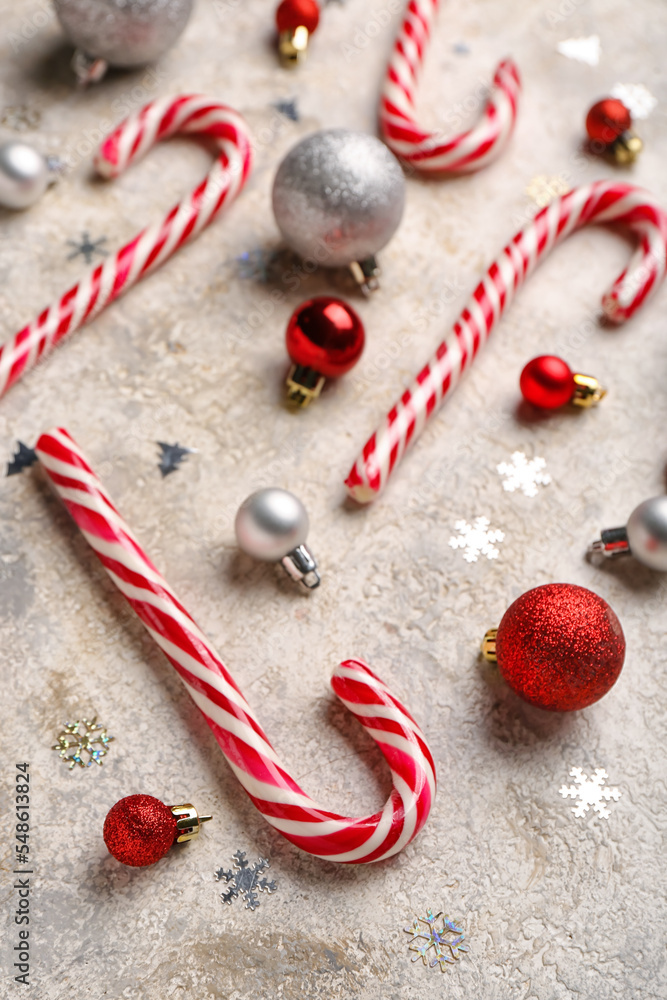 Composition with sweet candy canes and beautiful Christmas balls on light background