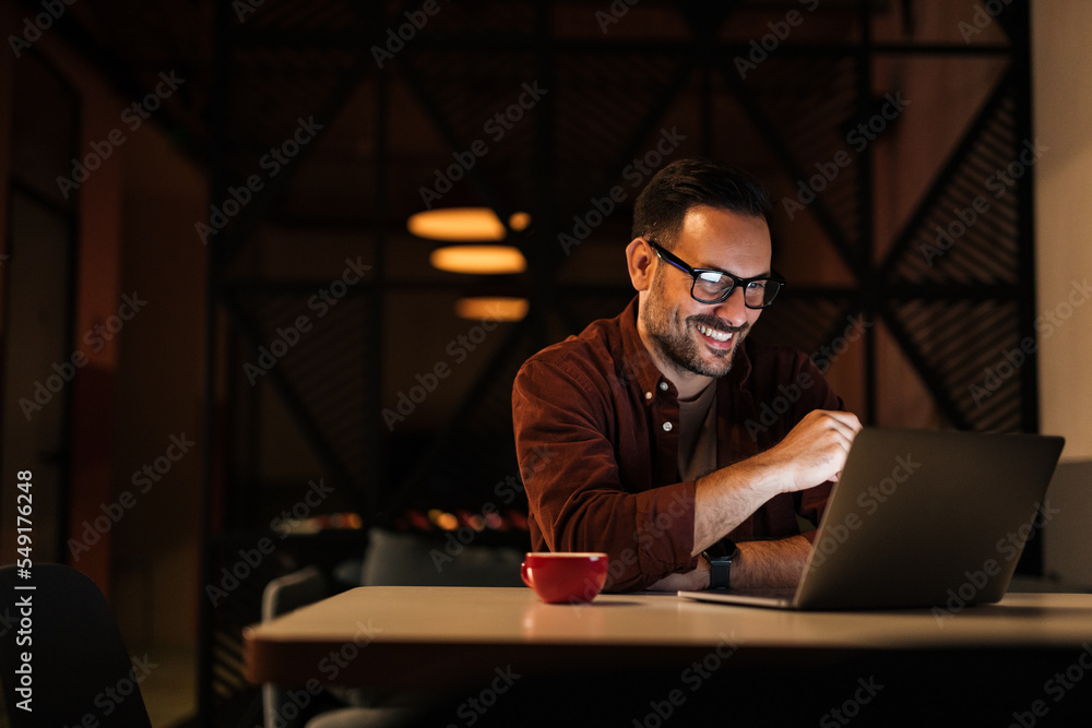 Smiling businessman working overtime, at the workplace.