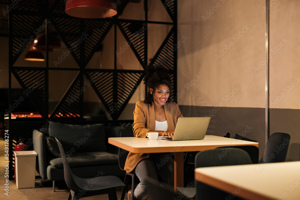 Businesswoman working overtime, at the office, using a laptop.