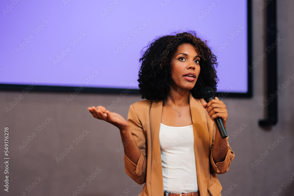 African businesswoman giving the lecture to the public, using and holding a microphone.