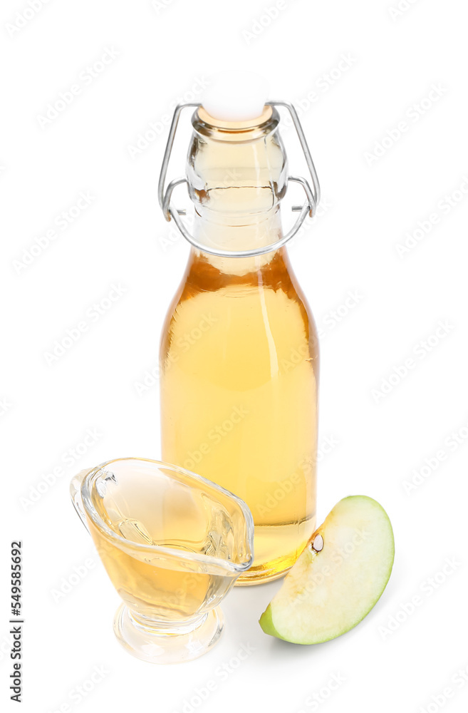 Bottle and gravy boat of apple cider vinegar on white background